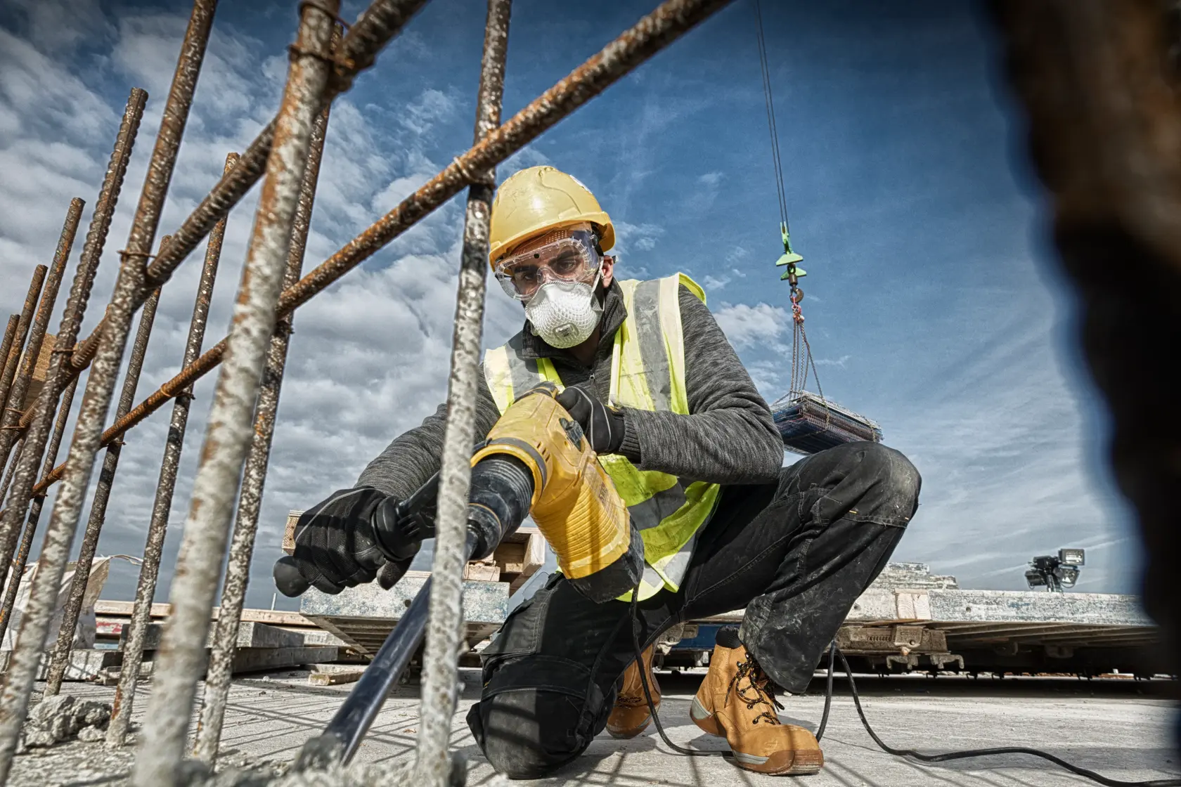 Arbeiter nutzt eine DEWALT-Bohrmaschine am Deckenbau, trägt Schutzkleidung und Warnweste.
