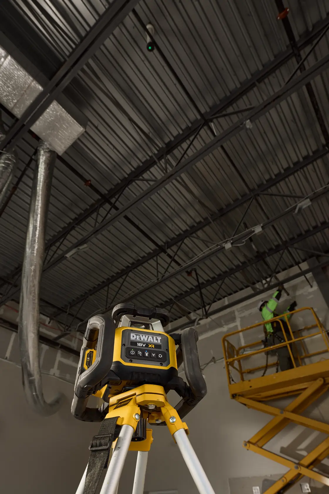 DEWALT DCLE35122GD1-QW, DCLE35122GD1 Lasergerät auf Stativ, Baustelle, Arbeiter auf Hebebühne nahe Decke.