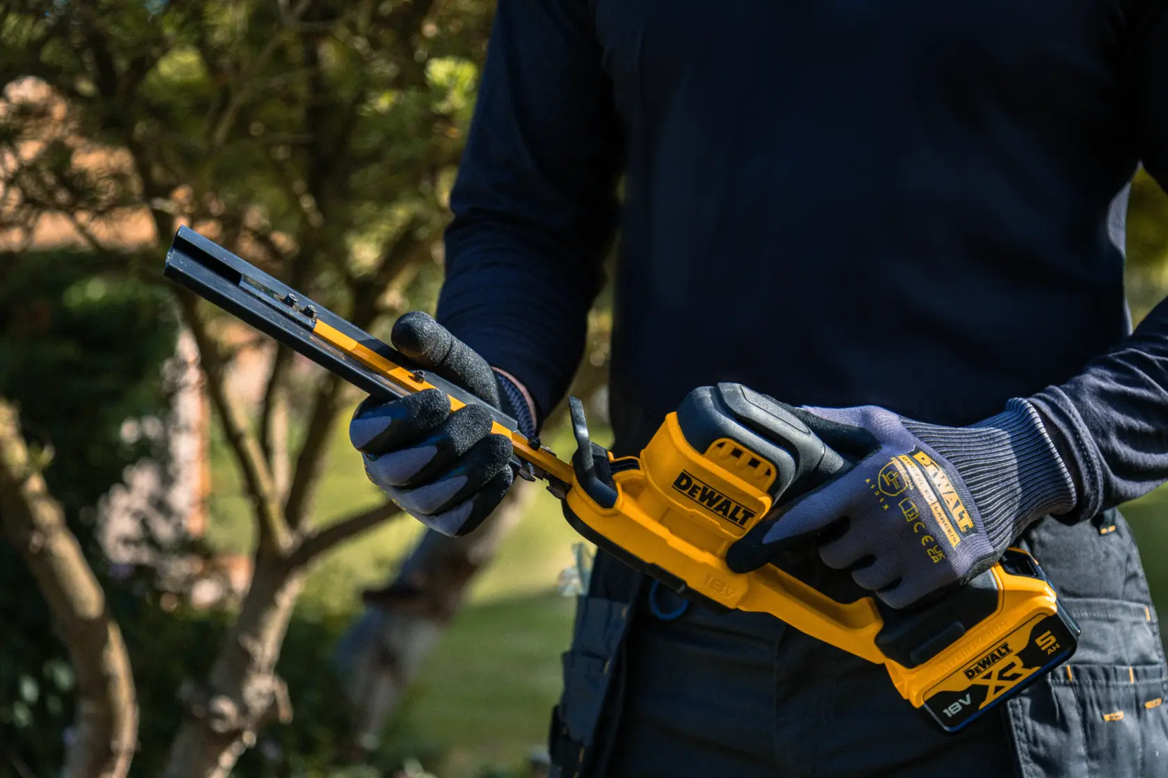 Persona usa herramienta DEWALT en jardín. SKUs: DCMHT520N-XJ, DCMHT520D1-QW, DCMHT520D1, DCMHT520N.