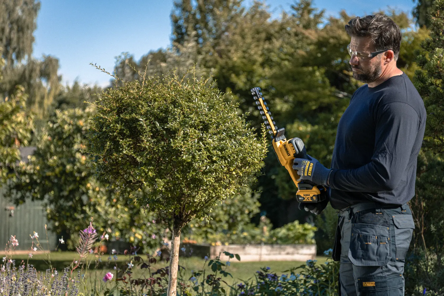 Persona usa cortasetos DEWALT DCMHT520N-XJ, DCMHT520D1-QW, DCMHT520D1, DCMHT520N al aire libre.