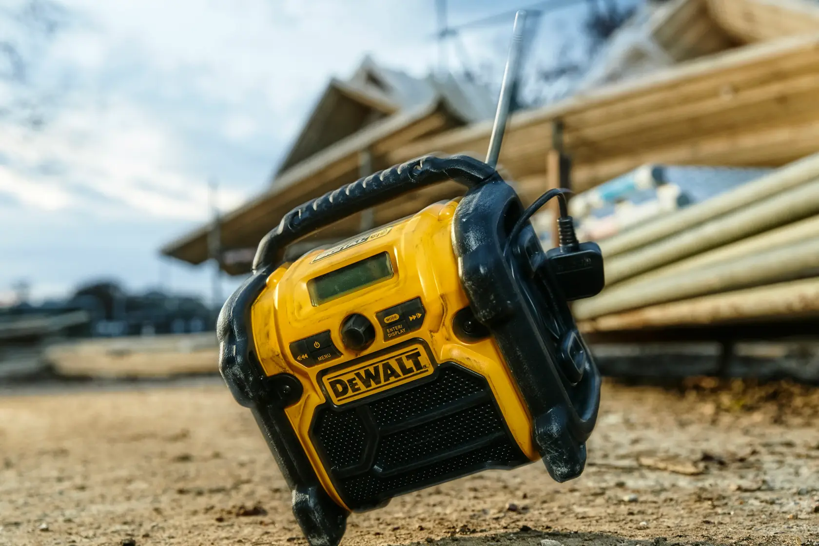 DEWALT DCR020 Radio im Freien auf einer Baustelle, Baumaterialien im Hintergrund.