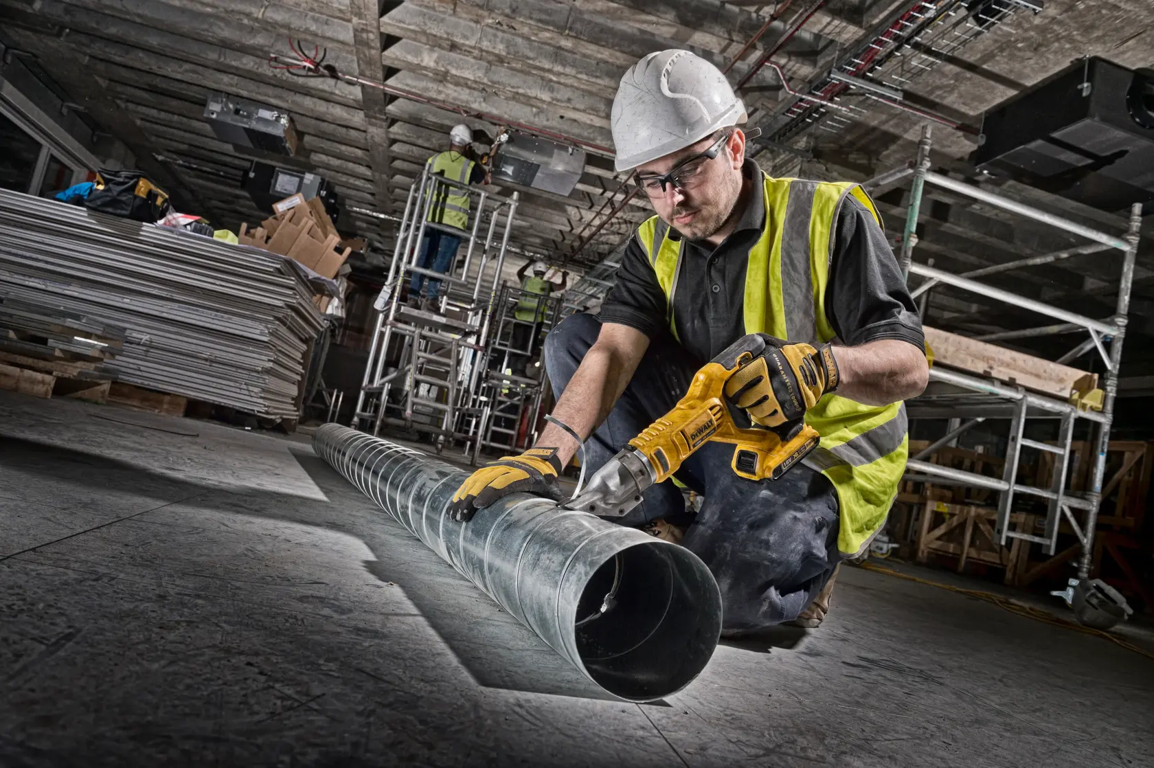 Arbeiter schneidet Metallrohr mit DEWALT Akku-Schere auf Baustelle.
