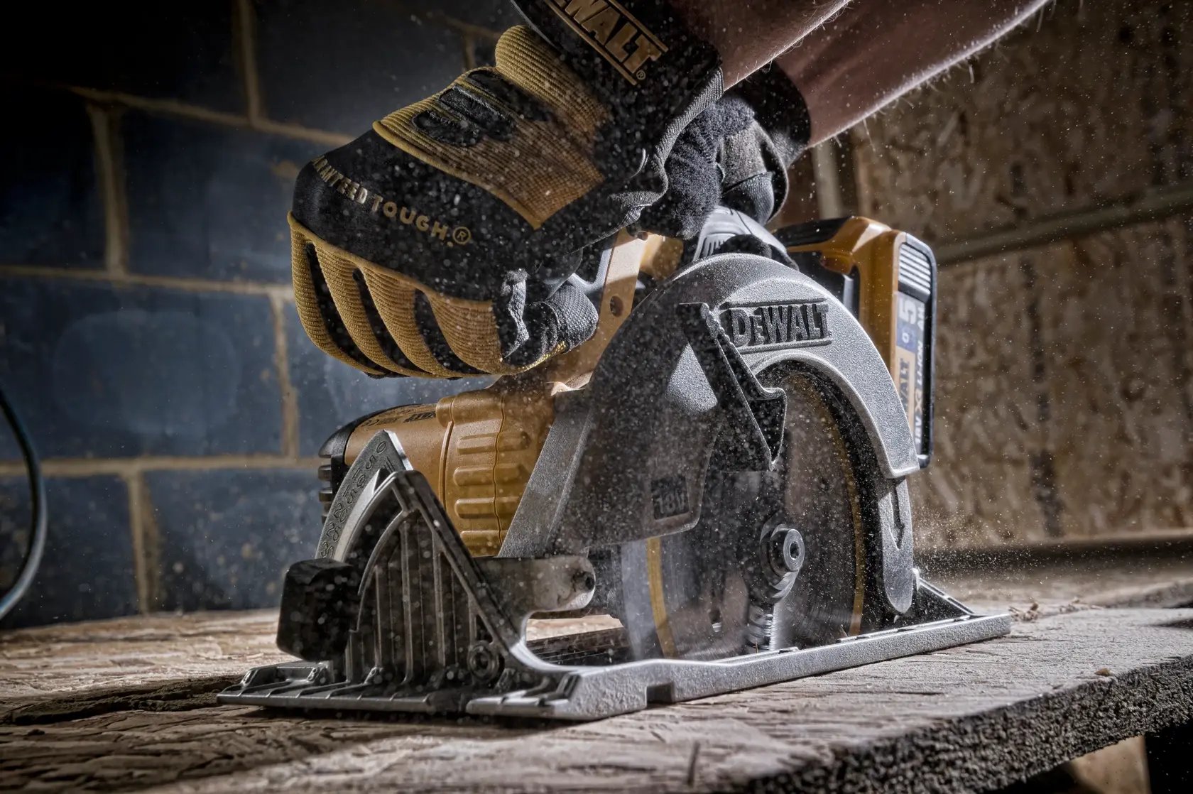 Hand mit Handschuh führt eine DEWALT Kreissäge zum Holz schneiden, Sägespäne fliegen im Werkraum.