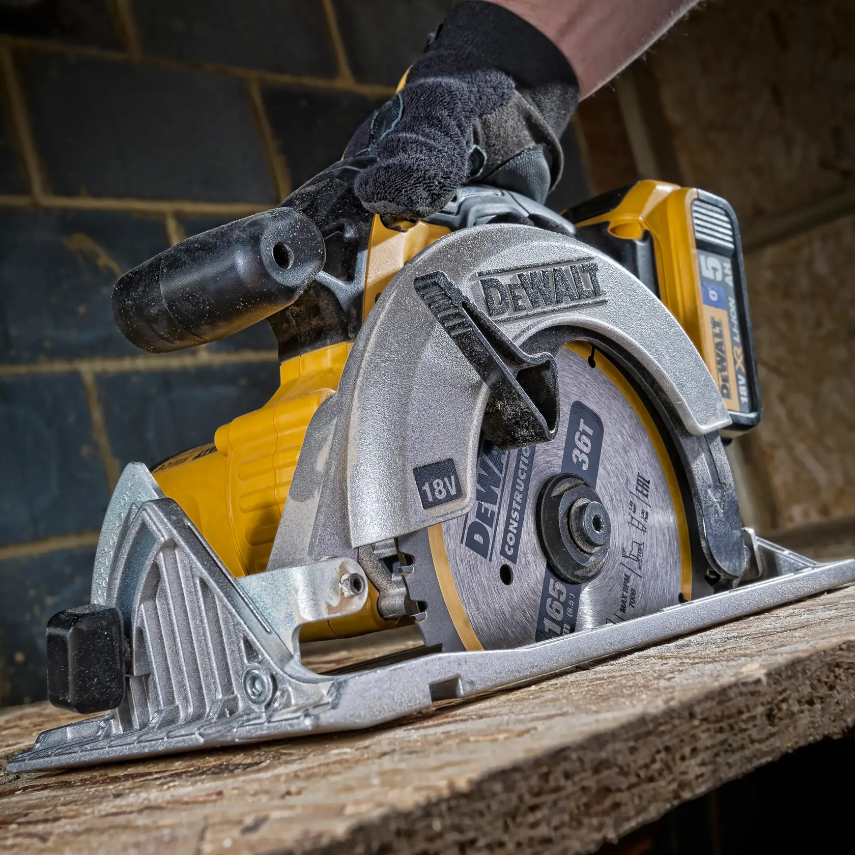 DEWALT DT1950 Akku-Kreissäge beim Holzschnitt, Nahaufnahme mit behandschuhter Hand.
