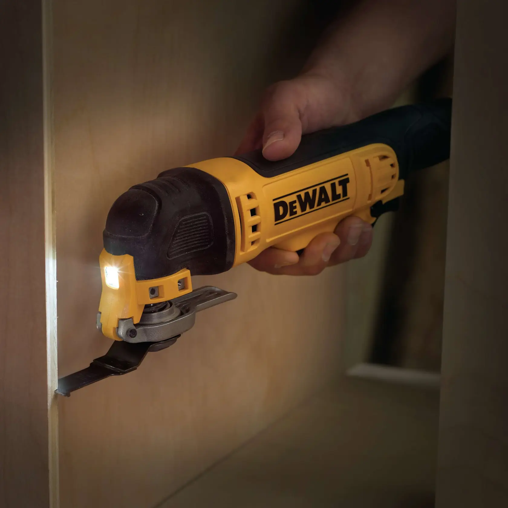 DEWALT Oszillationswerkzeug schneidet Holz in engem Bereich, von Hand gehalten, LED eingeschaltet.