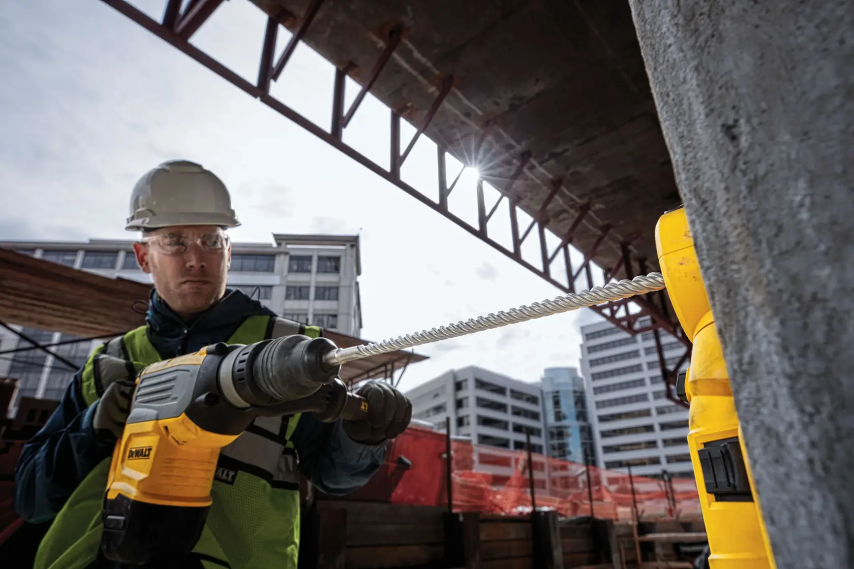 DEWALT-Bohrhammer im Einsatz auf Baustelle; Arbeiter bohrt Beton mit Schutzausrüstung.