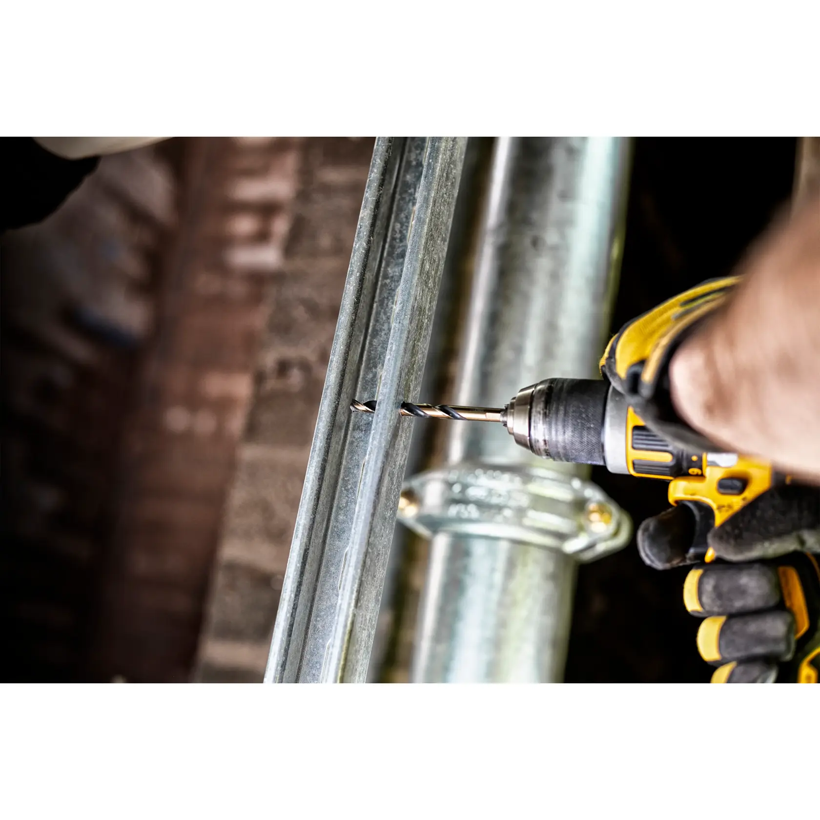 Person bohrt mit DEWALT-Bohrer ein Loch in einen Metallbalken und trägt Arbeitshandschuhe.
