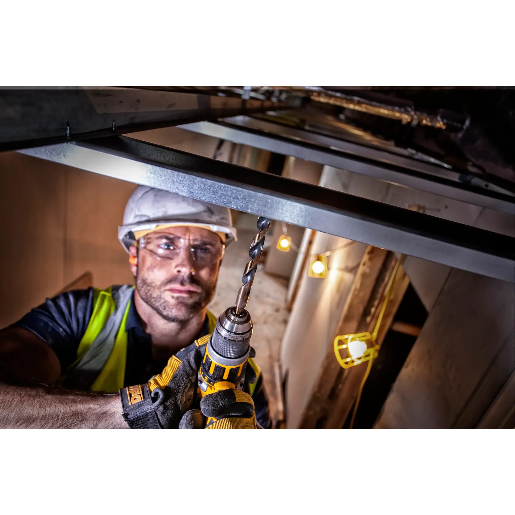 Arbeiter nutzt DEWALT-Bohrer mit DT70755 Bit zur Montage eines Metallrahmens auf Baustelle.