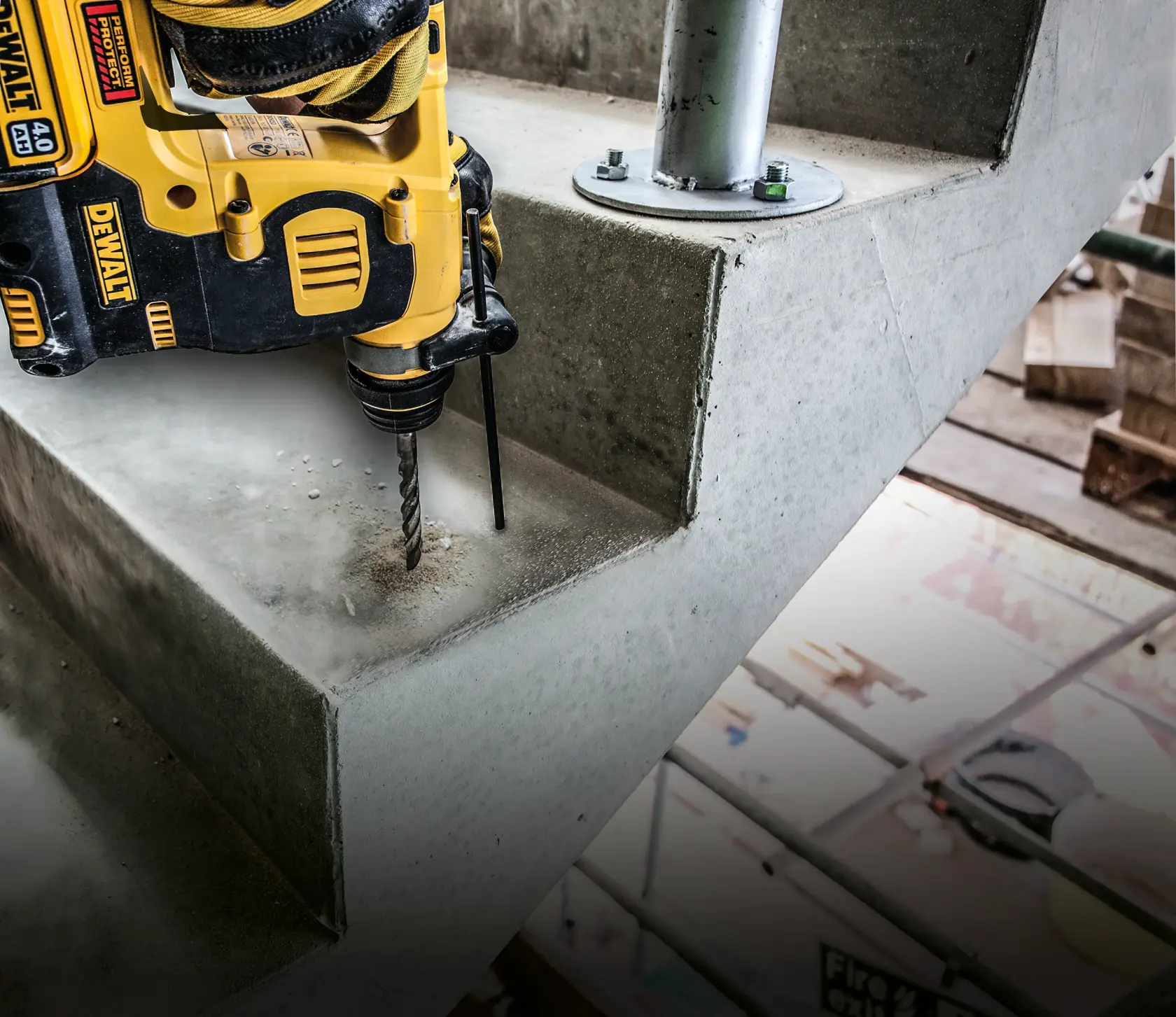 Taladro DEWALT perforando escalera de concreto cerca de soporte metálico, ambiente de construcción.