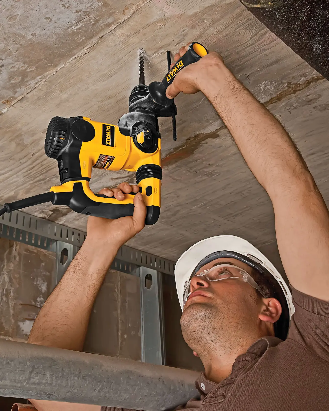 Persona usando taladro percutor DEWALT DT8938 para perforar un techo de concreto en obra.