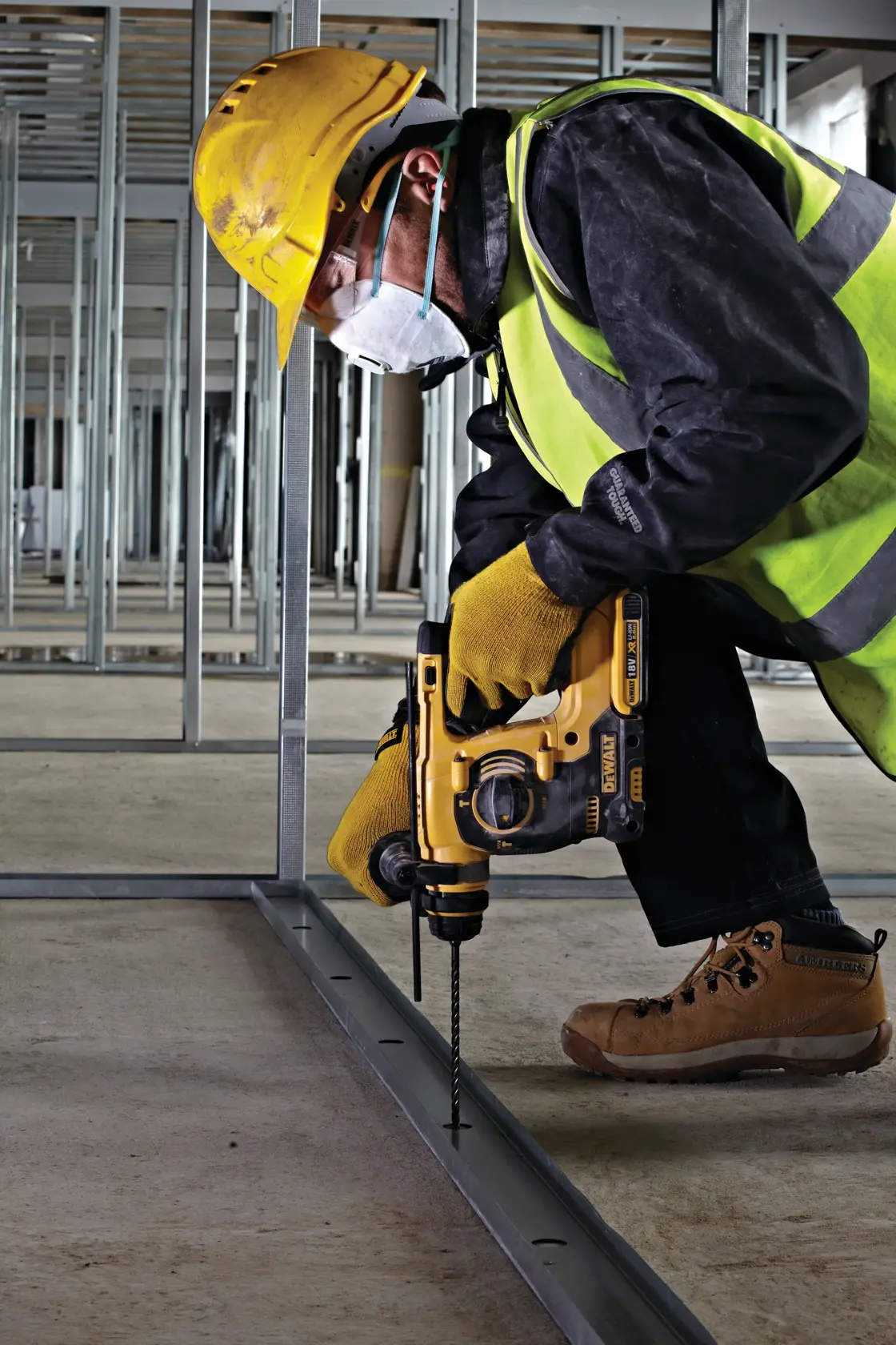 Trabajador con protección usa taladro DEWALT para perforar marco metálico en obra.