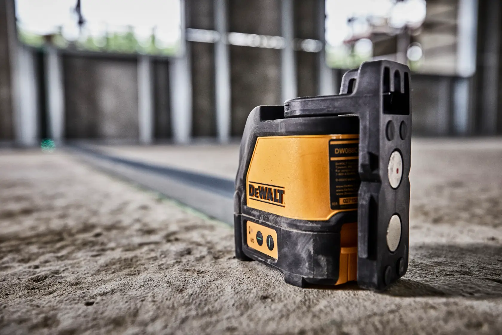 DEWALT grüner Laser DW088CG auf Baustellenboden für präzises Ausrichten.