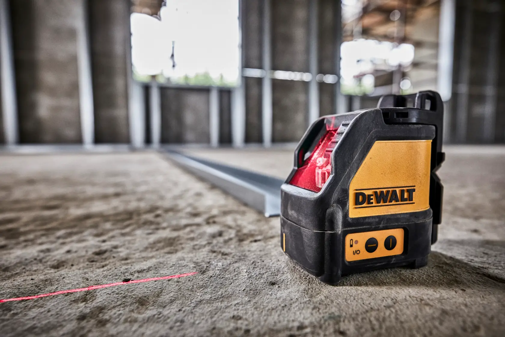 DEWALT Laser-Nivelliergerät erzeugt eine rote Linie auf einem Bauplatzboden für genaue Messungen.