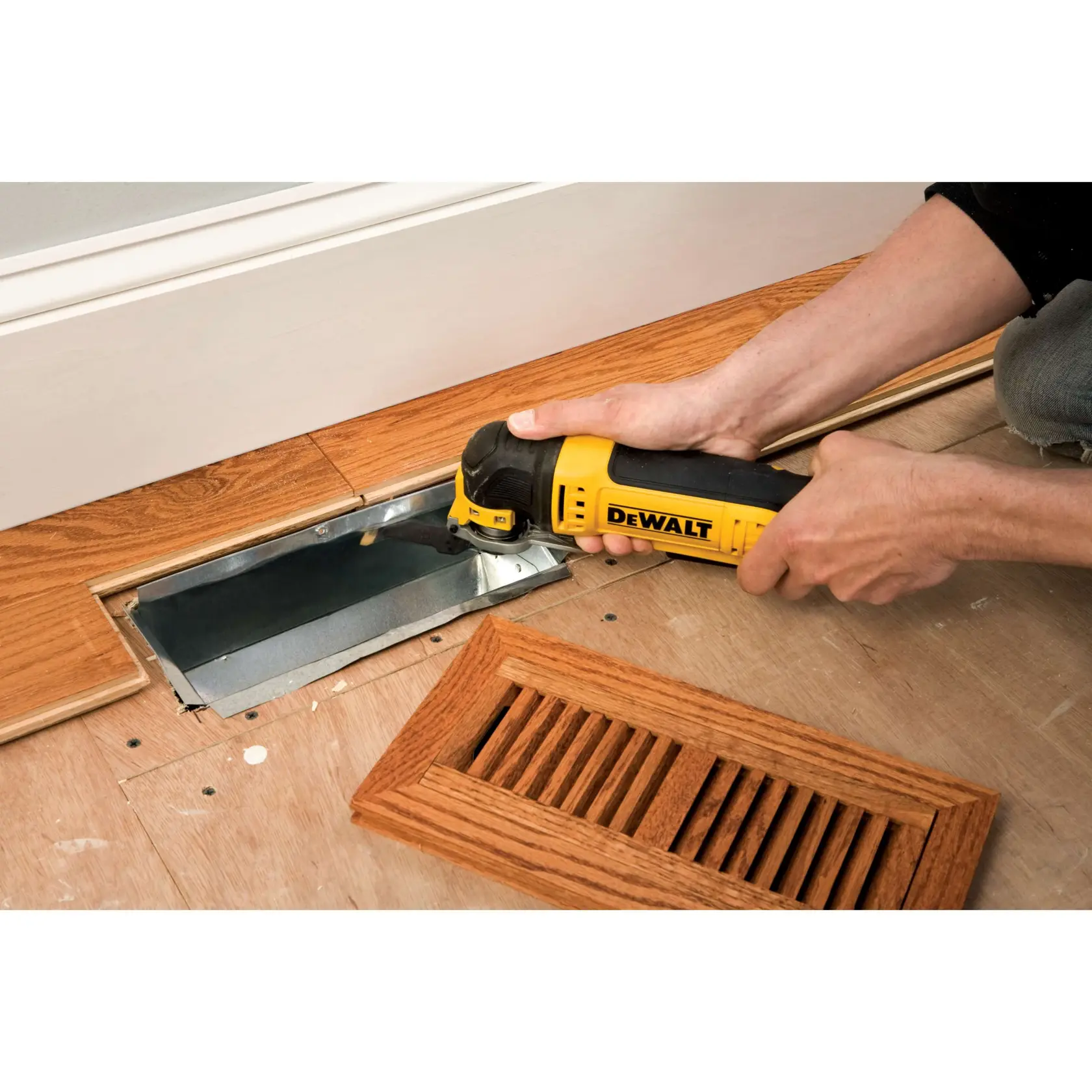 Person schneidet mit einem DEWALT Multitool Holzboden nahe einem Lüftungsgitter.