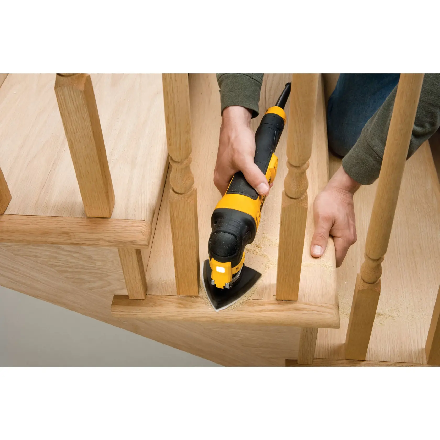 Person schleift Holztreppe mit einem DEWALT Multitool zwischen Treppenstäben.