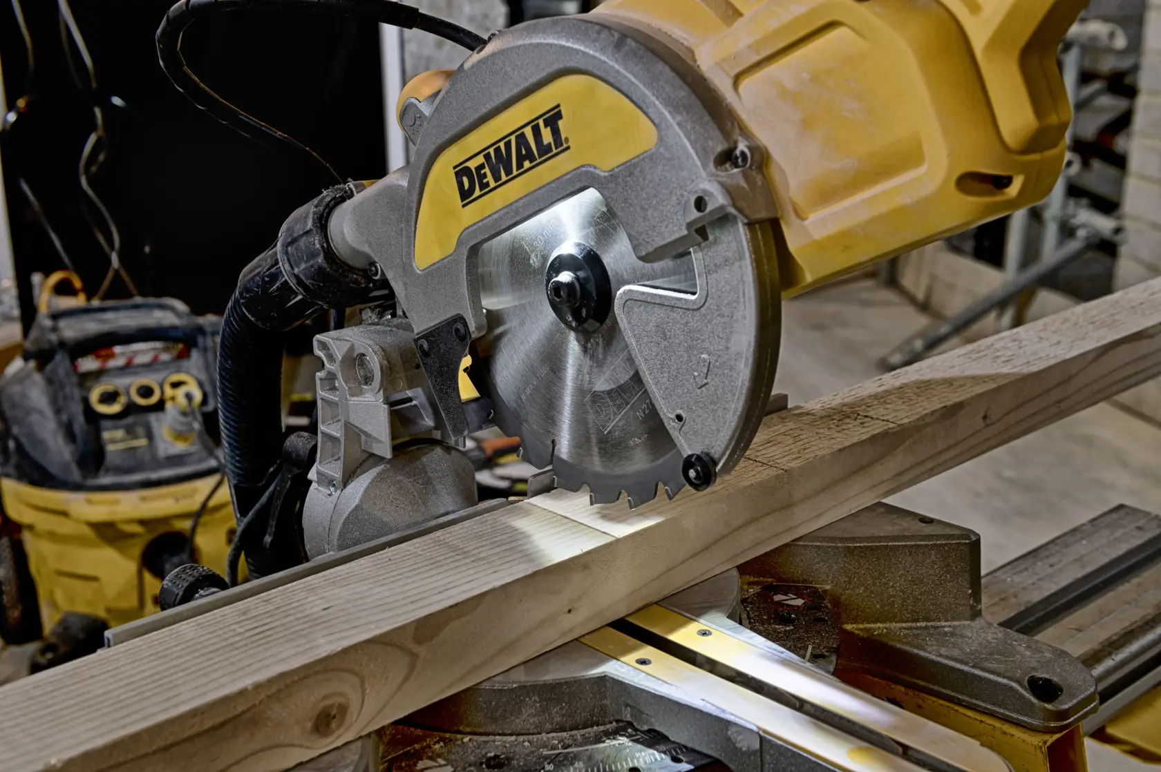 Sierra de inglete DEWALT cortando una tabla de madera en taller.