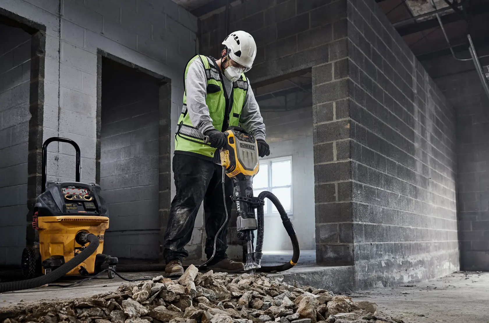 Arbeiter nutzt DEWALT Abbruchwerkzeug mit Staubsauger auf Baustelle und bricht Betontrümmer.