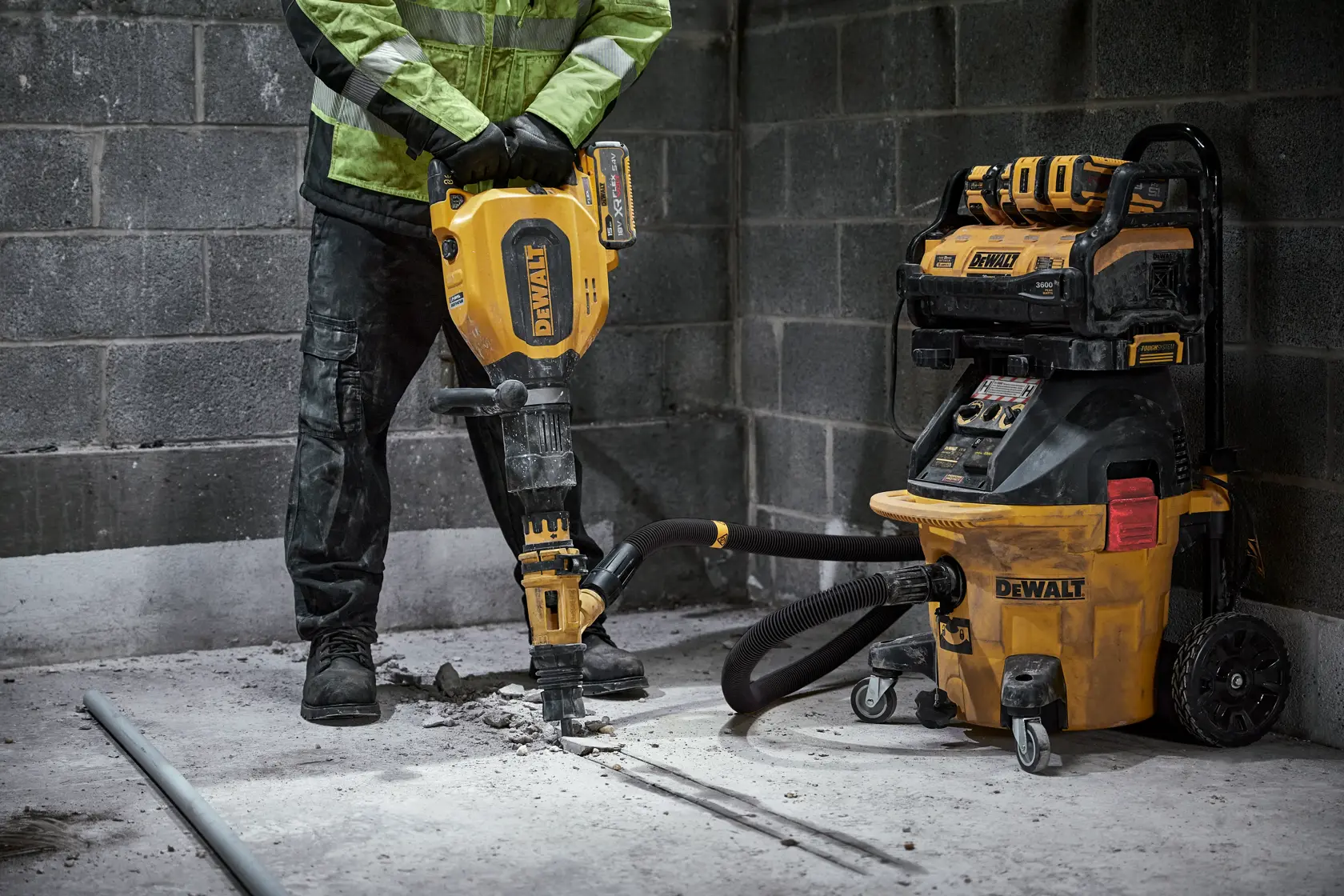 DEWALT-Arbeiter nutzt einen Abbruchhammer mit DWV905H Staubabscheider in einem Betonraum.